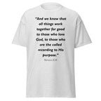 Unisex black t-shirt with Romans 8:28 Bible verse printed in black text on front