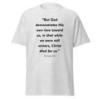 Unisex black t-shirt with Romans 5:8 Bible verse printed in black text on front
