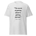 Unisex black t-shirt featuring Mark Twain Getting Ahead quote typography printed across the front chest