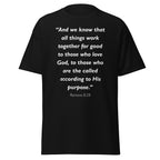 Unisex black t-shirt with Romans 8:28 Bible verse printed in white text on front
