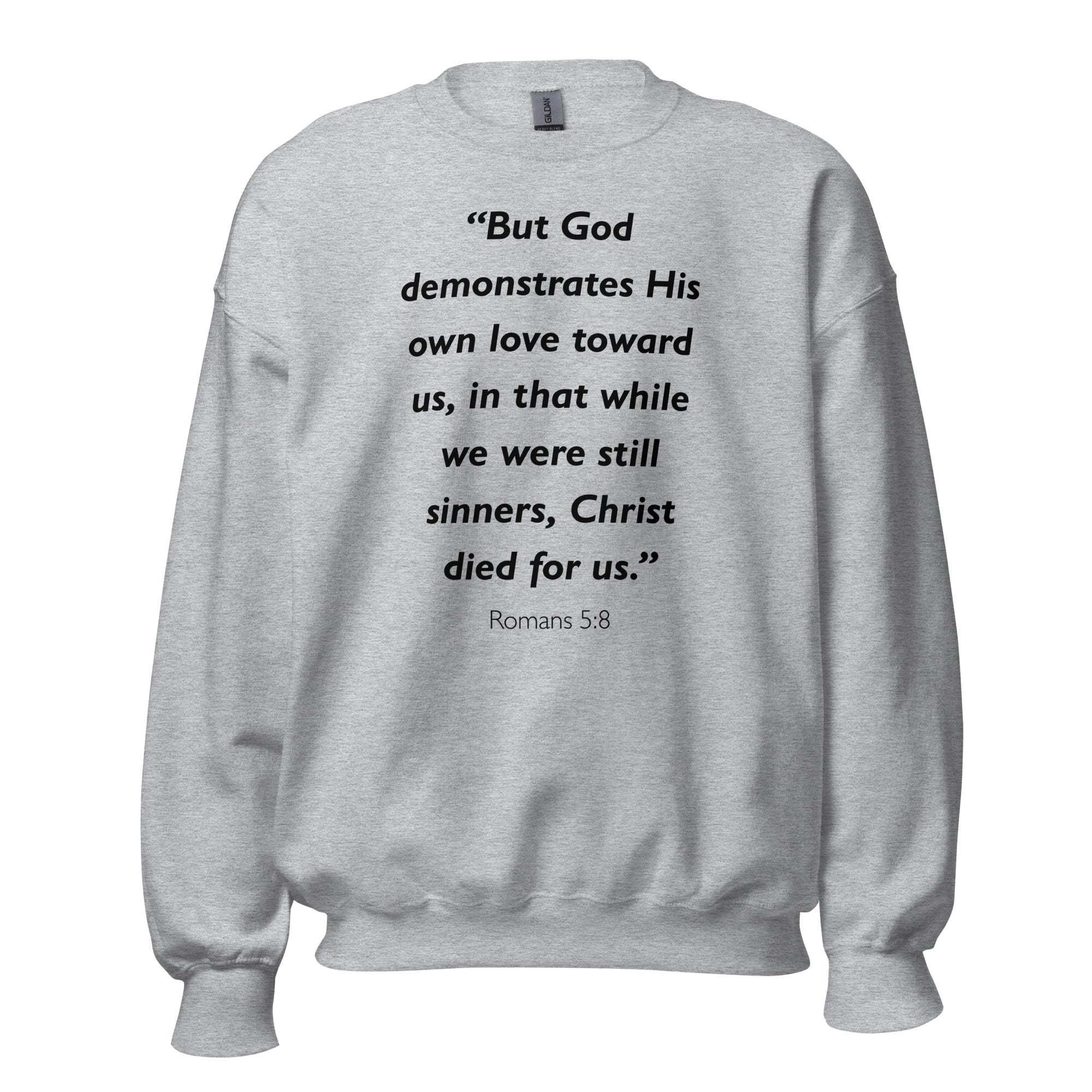 Unisex black sweatshirt with Romans 5:8 Bible verse printed in black text on front