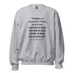 Unisex black sweatshirt with 2 Corinthians 5:17 Bible verse printed in black text on front