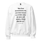 Unisex navy blue sweatshirt with Romans 5:8 Bible verse printed in black text on front