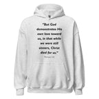 Unisex black hoodie with Romans 5:8 Bible verse printed in black text on front
