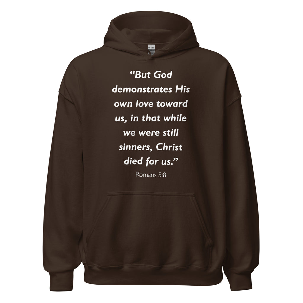 Unisex black hoodie with Romans 5:8 Bible verse printed in white text on front
