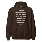 Unisex black hoodie with Romans 5:8 Bible verse printed in white text on front