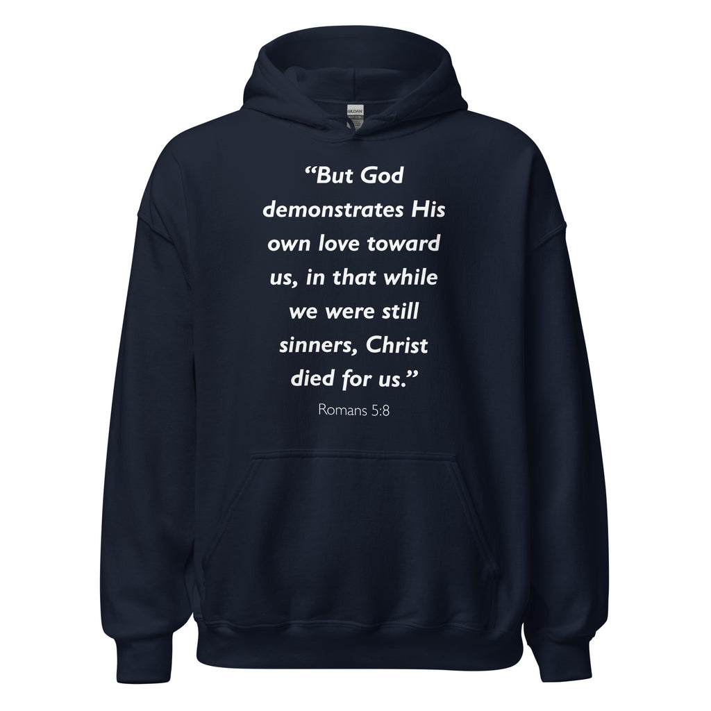 Unisex navy blue hoodie with Romans 5:8 Bible verse printed in white text on front